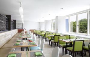 una sala da pranzo con tavoli lunghi e sedie verdi di Hotel Santika Kelapa Gading a Giacarta
