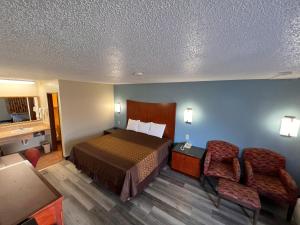 ein Hotelzimmer mit einem Bett und zwei Stühlen in der Unterkunft Briarwood Inn in Amory