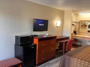 ein Hotelzimmer mit einem Bett und einem Schreibtisch mit einem TV in der Unterkunft Briarwood Inn in Amory