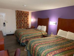 ein Hotelzimmer mit 2 Betten und einer lila Wand in der Unterkunft Briarwood Inn in Amory
