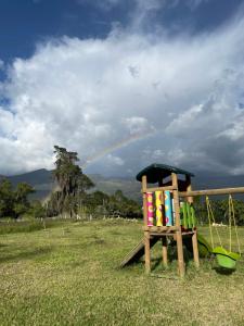 a wooden chair in a field with a rainbow in the sky at Cucuate Hospedaje in Choachí