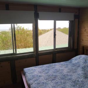 a bedroom with three windows with a bed and a view at Casita con vista al mar in Salinas 