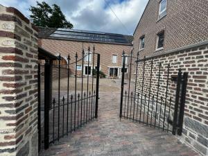 een ijzeren poort voor een bakstenen gebouw bij Farm with indoor pool and bubble bath in Houyet