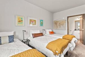 una stanza con tre letti bianchi con coperte arancioni di New 2 Bed 2 Bath Near Perry District and DT a Spokane