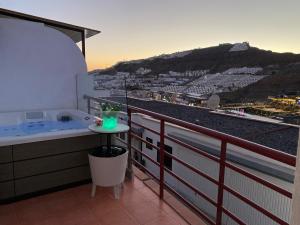 einen Balkon mit einer Badewanne und Stadtblick in der Unterkunft Villa Mogan Mall, con jacuzzi y PlayStation 5 in Puerto Rico de Gran Canaria