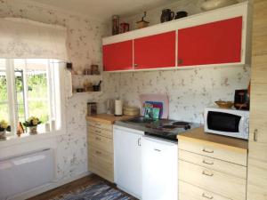 a kitchen with red cabinets and a white microwave at Holiday home RAMSJÖ III in Ramsjö