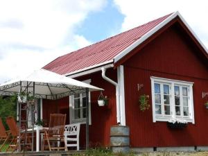 a red house with a table and chairs and an umbrella at Holiday home RAMSJÖ III in Ramsjö