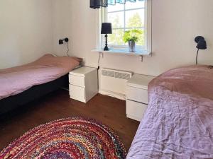 een slaapkamer met 2 bedden, een raam en een tapijt bij 4 person holiday home in HÅCKSVIK-By Traum in Håcksvik +22 foto's