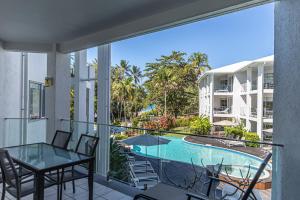 a balcony with a table and chairs and a swimming pool at Beaches Holiday Apartments - Official Onsite Reception & Check In in Port Douglas