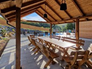 una mesa de picnic de madera y sillas bajo un pabellón en Comfortable holiday home with a swimming pool for 12 people en Iwierzyce