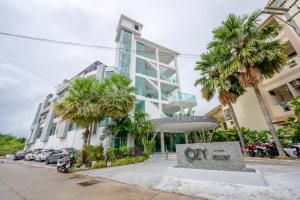 een gebouw met palmbomen ervoor bij Cozy Resort, A Boutique Hotel in Pattaya South
