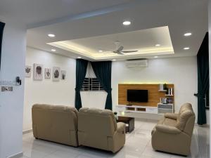 uma sala de estar com 2 sofás e uma televisão de ecrã plano em 4 bedrooms (private bathroom) Perdana Hill Villa em Lahad Datu