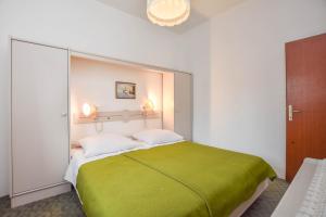 a bedroom with a large bed with a green blanket at Apartments Promina in Biograd na Moru