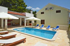 a swimming pool with chairs and umbrellas next to a house at Villa Korcula in Prizba