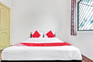 1 dormitorio con 1 cama grande con almohadas rojas en OYO Shree Balaji Lodging, en Chikalthān