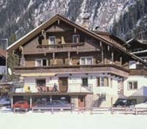 ein großes Haus im Schnee vor einem Berg in der Unterkunft Pension Steiner in Mayrhofen