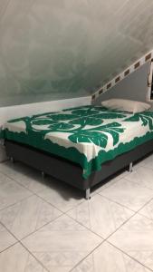 a bed with a green and white blanket on it at Manate hebergement in Faaa
