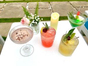 Una mesa blanca con tres bebidas. en Malis Homestay, en Trà Vinh