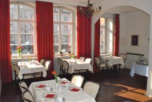 a restaurant with white tables and red curtains and windows at Hotel am Kornmarkt in Heidelberg