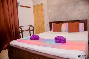 a bedroom with two beds with purple hats on them at Blooming polhena in Matara