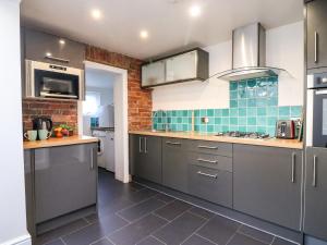 une cuisine avec des placards gris et un mur en briques dans l'établissement South Harbour Cottage, à Weymouth