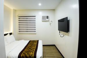 um quarto com uma cama e uma televisão de ecrã plano em PRIMELUXE HOTEL em Cagayan de Oro