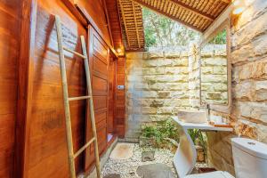 a bathroom with a toilet and a stone wall at Bila Penida Resort & Farm in Nusa Penida