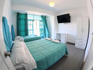 a bedroom with a green bed and a television at AQUAMARINE PARACAS Beach Hostal in Paracas