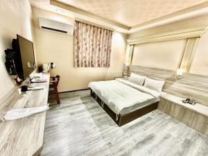 WL HOTEL Hsinchu في مدينة هسينشو: غرفة نوم فيها سرير وتلفزيون