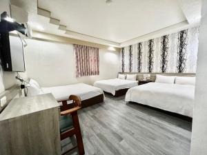 um quarto de hotel com duas camas e uma televisão em WL HOTEL Hsinchu em Hsinchu