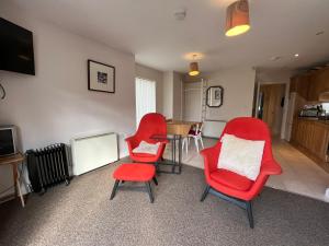 uma sala de estar com cadeiras vermelhas e uma mesa em Sandymount House & Garden em Dublin