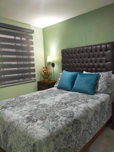 a bedroom with a large bed with blue pillows at Luxury departament Centenario in Guadalajara
