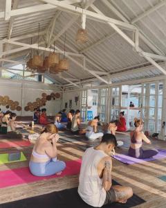 un grupo de personas sentadas en una clase de yoga en 7SEAS Cottages en Gili Air