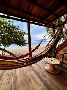 a hammock on a deck with a view of the beach at Coco Lodge, vista al mar in La Poza