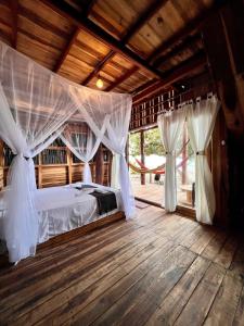 a bedroom with a bed with curtains and a wooden floor at Coco Lodge, vista al mar in La Poza