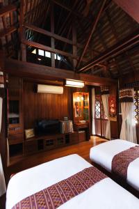 two beds in a room with wooden walls at Baansuwanburi in Chiang Mai