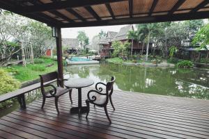 a porch with a table and two chairs and a pond at Baansuwanburi in Chiang Mai