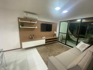 a living room with a couch and a tv at Iloa Residence Luxo in Barra de São Miguel