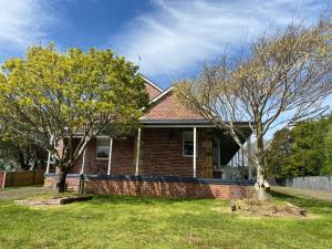 a brick house with two trees in the yard at Lady Heleena's At Strahan in Strahan