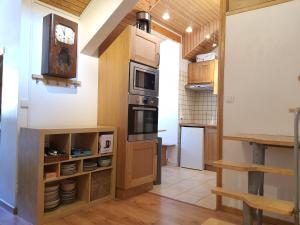kuchnia z drewnianymi szafkami i zegarem na ścianie w obiekcie Appartement dernier étage 3 chambres - Olympe w mieście Les Deux Alpes
