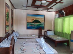 a room with two beds and a couch and a painting at Ferranco Tourist Inn in San Vicente