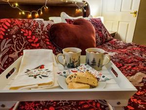 a tray with cookies and two cups of coffee on a bed at Marleys Retreat in Seaton Delaval