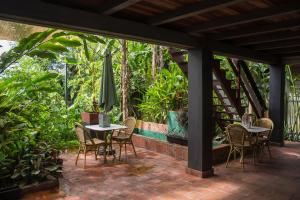 un patio con mesas, sillas y una sombrilla en Couleur Locale Paramaribo, en Paramaribo