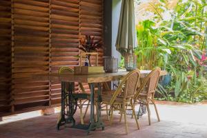 Couleur Locale Paramaribo في باراماريبو: طاولة خشبية مع كراسي ومظلة على الفناء