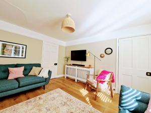 a living room with a green couch and a tv at Cheerful 3 bed Grade II Central Cottage in Cirencester
