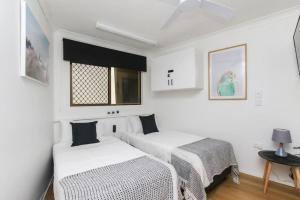 two beds in a room with white walls at Modern Apartment Close to the City Centre 16 in Cairns