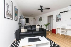 a living room with a black leather couch and a table at Modern Apartment Close to the City Centre 16 in Cairns