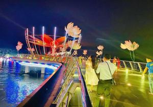 a group of people walking on a pier at night at KHÁCH SẠN THU NGUYỄN - ngay BẾN NINH KIỀU, CHỢ ĐÊM in Can Tho