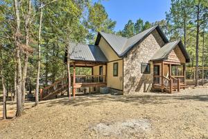 a house with a porch and a deck in the woods at Modern Broken Bow Cabin, Near Lake and Wineries in Broken Bow