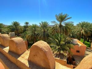 a view of a desert with palm trees and buildings at Bait Aljabal Hospitality Inn in Al Ḩamrāʼ